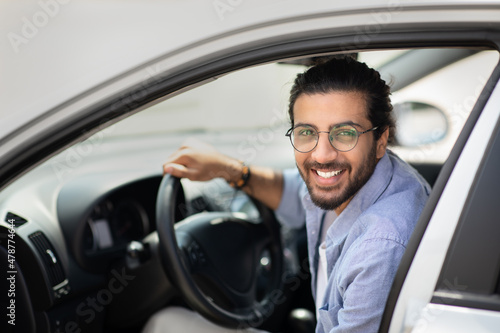 Portrait of happy arab guy getting into brand new car