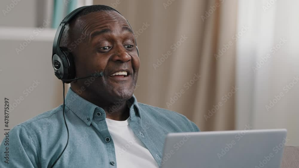 Close-up adult african american man in headphones communicating on webcam on laptop using video calling app hotline operator speaks into microphone uses headset male conducts webinar during quarantine Close-up adult african american man in headphones communicating on webcam on laptop using video calling app hotline operator speaks into microphone uses headset male conducts webinar during quarantine