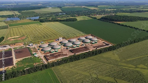 Biotechnological plant for recycling biowaste into energy. Round reservoirs for storage and processing biomass. Beautiful nature at the backdrop.