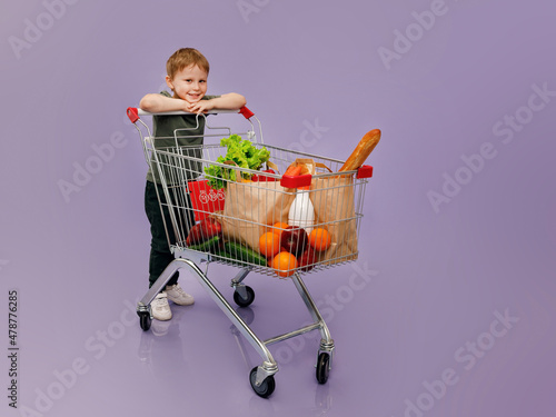 A boy smiles sitting in a grocery cart. Isolated concept image of the shopping with cjpe space.