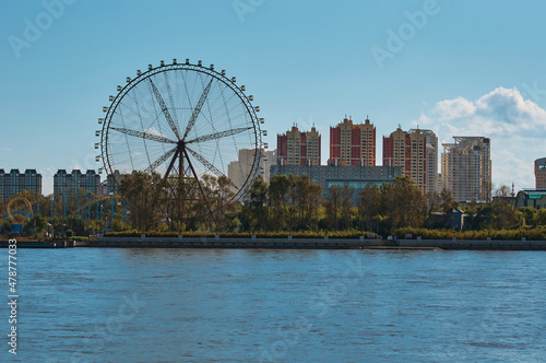 Ferris wheel and amusement park on the Amur River, Heihe city, China. View from the coast of the city of Blagoveshchensk, Russia.