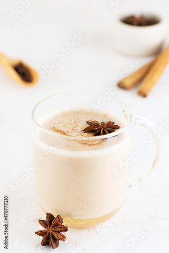 Masala chai with milk, anise, cinnamon, ginger, pepper in a glass cup. Selective focus.