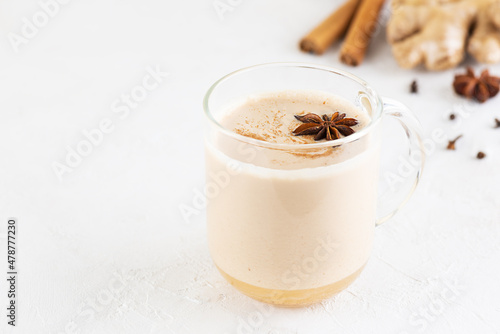 Vegan masala tea with coconut milk and spices in a glass mug. Selective focus. Horizontal orientation, copy space.