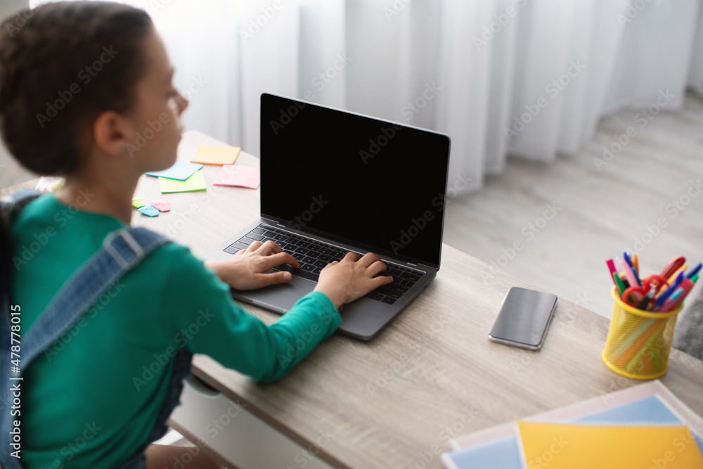 Girl sitting at desk, using blank laptop, typing on keyboard Girl sitting at desk, using blank laptop, typing on keyboard