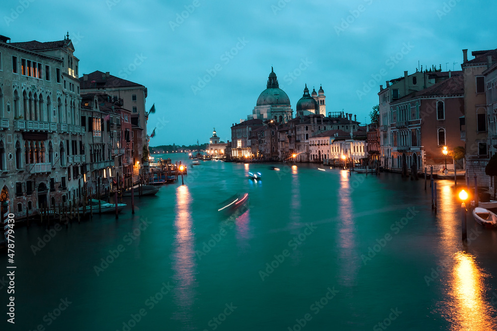 Late evening canals with boats, lanterns and motion blurs in dark. Venice.