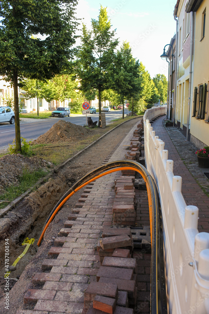 Fototapeta premium Tiefbauarbeiten bei Glasfaser-Ausbau für schnelles Internet und DSL mit Absperrung und Kabelverlegung