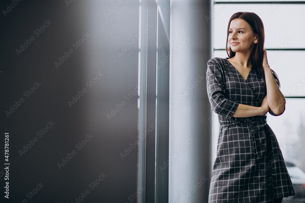 Young woman in a car showroom choosing a car Young woman in a car showroom choosing a car