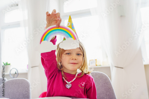 A cute little girl shows colorful rainbows at a birthday party