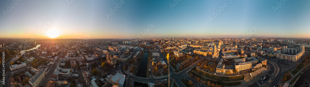 Wide panoramic aerial view above river Lopan embankment near Annunciation Cathedral in Kharkiv, Ukraine. Flagpole with flag of Ukraine and sunny autumn cityscape, city streets with traffic