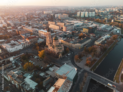 Sunny sunset aerial view above river Lopan embankment near Annunciation Cathedral in Kharkiv, Ukraine. Autumn cityscape, city streets