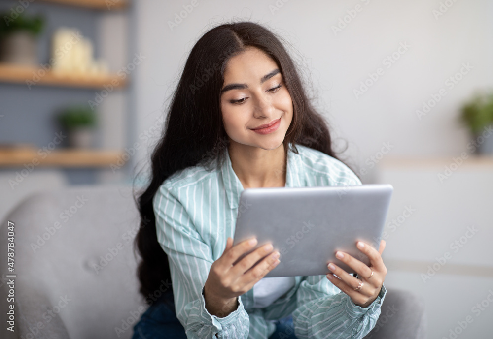 Charming Indian lady using tablet computer, studying remotely or having online conference at home Charming Indian lady using tablet computer, studying remotely or having online conference at home