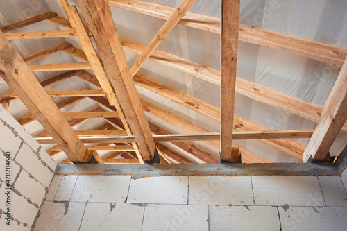 Construction of a new building and a wooden roof made of planks and beams. Inside view