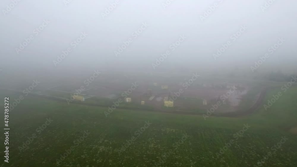 Aerial view on oil pumps at oilfield cluster in a foggy field after rain. Muddy ground puddles hard working conditions. Aerial view on oil pumps at oilfield cluster in a foggy field after rain. Muddy ground puddles hard working conditions.