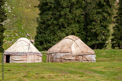 Two Kyrgyz yurts on grass in middle of the mountains. Yurts are traditional national buildings of local residents, ala-kul lake Terskey Alatau mountain range, Kyrgyzstan, Central Asia.