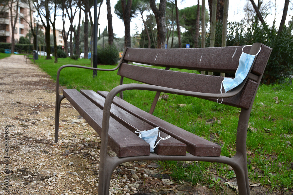 Used protective mask abandoned on a park bench. Used Protective masks abandoned during the Coronavirus pandemic on public places. Used protective mask abandoned on a park bench. Used Protective masks abandoned during the Coronavirus pandemic on public places.