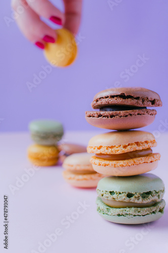 Fototapeta Naklejka Na Ścianę i Meble -  Feminine hand with macarons dessert on pastel tones background. Copy space.