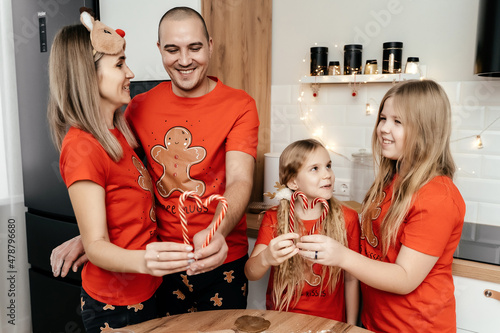 A family in Christmas pajamas cooking ginger cookies in the kitchen