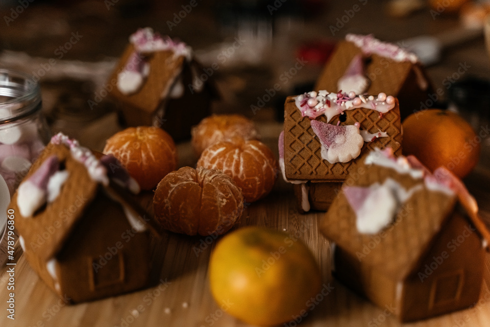 Christmas cooking gingerbread houses and ginger cookies on the kitchen table with tangerines. Christmas cooking gingerbread houses and ginger cookies on the kitchen table with tangerines.