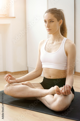 Sporty young woman doing yoga at home