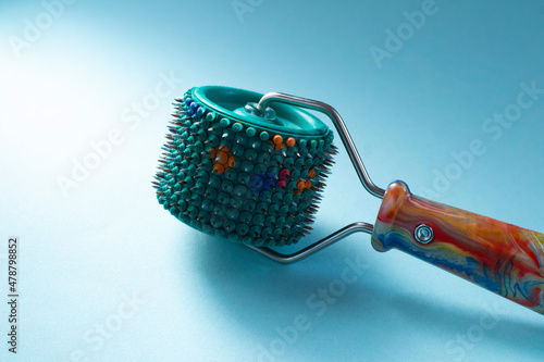 Roller Lyapko for massage and rehabilitation on a blue background. Device massager Lyapko with needles. Spiky roller with metal needles. 