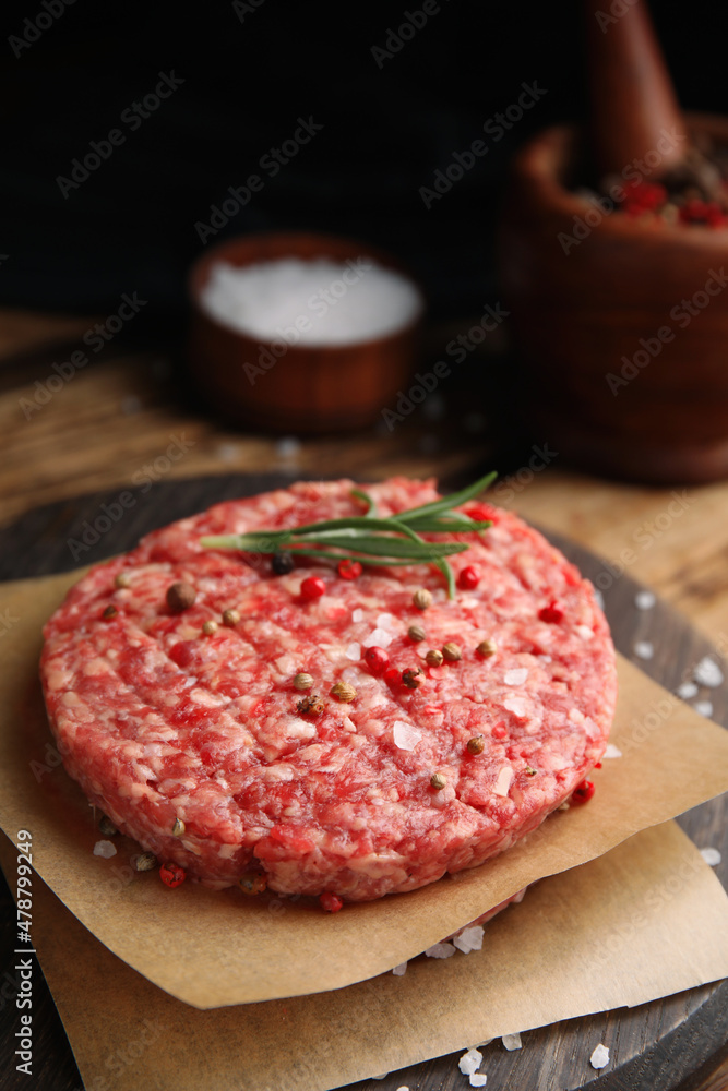 Raw hamburger patties with rosemary and spices on wooden board, closeup Raw hamburger patties with rosemary and spices on wooden board, closeup