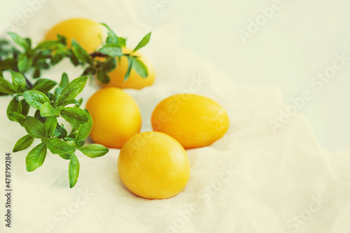 Yellow Easter eggs on a white napkin, decorated with green willow branches on a light background, toned, soft selective focus, copy space. Festive background with Easter symbols