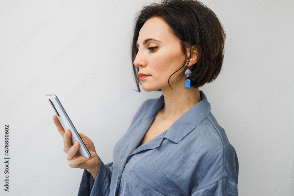 Bruinette woman in pajama working online with smartphone in hands at home. Female using phone looking at screen typing message, using telephone technology doing online job, surfing internet social Bruinette woman in pajama working online with smartphone in hands at home. Female using phone looking at screen typing message, using telephone technology doing online job, surfing internet social