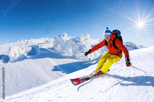 Skier skiing downhill in high mountains against blue sky photo