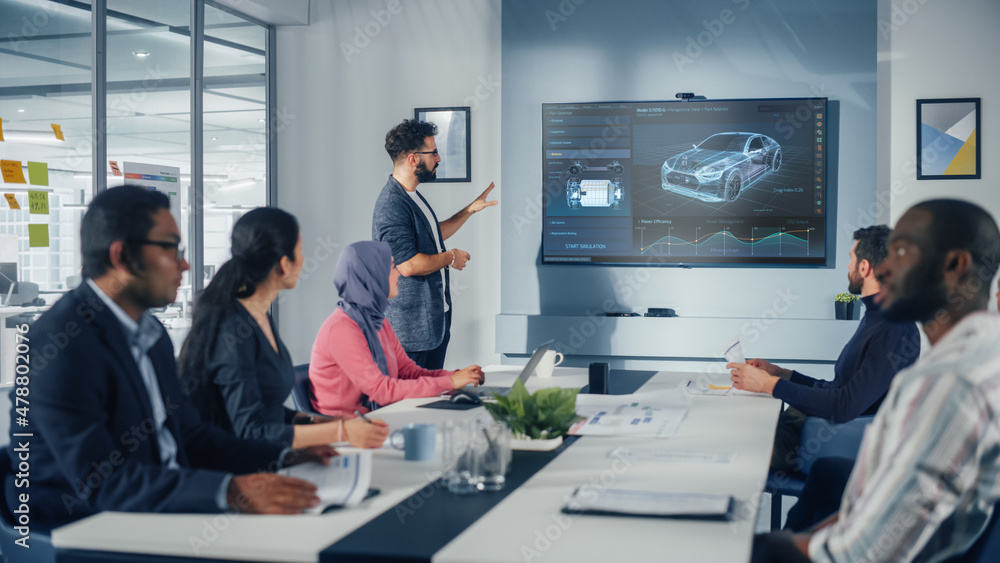 © Gorodenkoff - Multi-Ethnic Office Conference Room Meeting: Hispanic Industrial Engineer Presents Car Concept to a team of Technicians Talk, Use TV with 3D Vehicle Prototype Concept. Eco-friendly, Green Energy