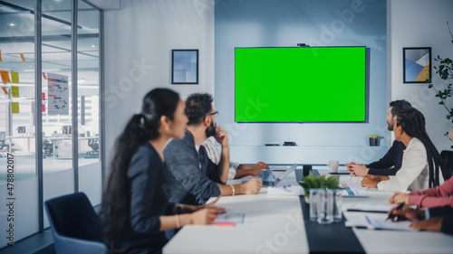 Multi-Ethnic Office Conference Room Meeting: Diverse Team of Successful Managers, Executives Talk, Use Green Screen Chroma Key TV. Businesspeople Investing in eCommerce Startup. photo