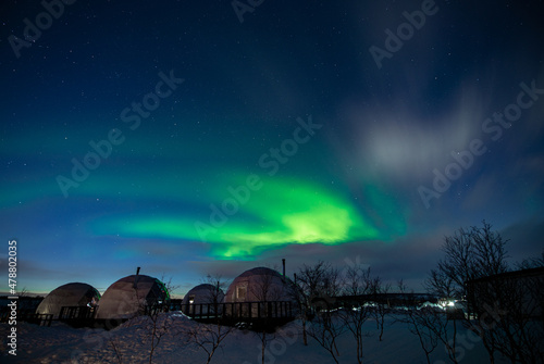 Northern Lights also known as aurora  borealis or polar lights at cold night over igloo village. Beautiful night photo of magic nature of winter landscape