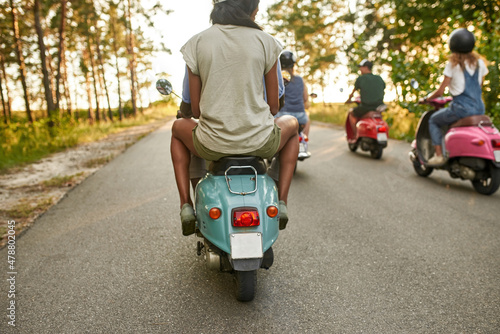 Foto Selective focus on young multiracial people riding scooters