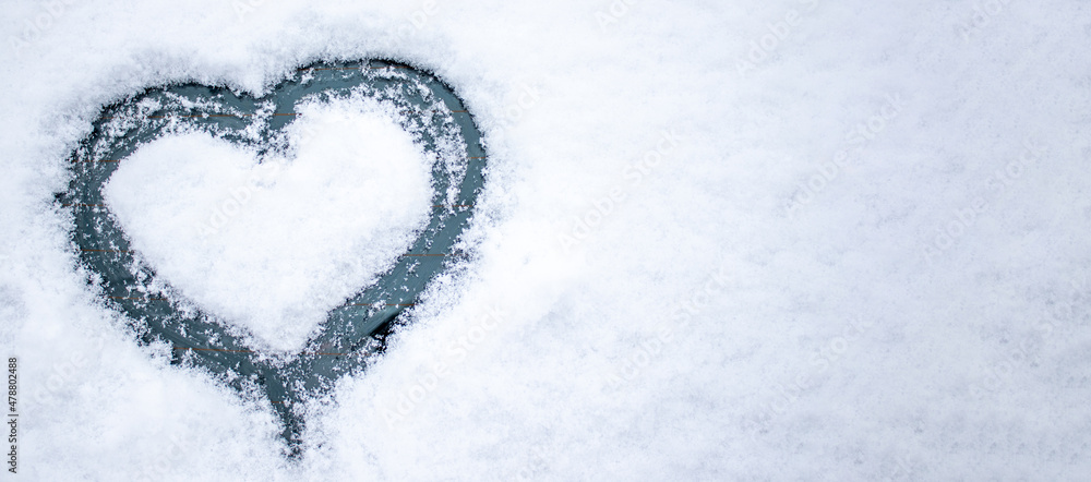 heart shape drawn in snow, on a car window. love and valentine's day concept. winter time, cold and frozen love. space for text banner for advertising.
