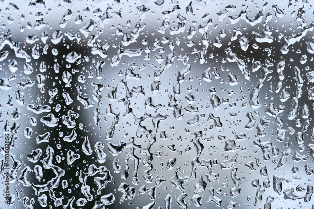 Texture of frozen water drops on the glass. Dark triangle silhouette on the background. High quality macro photo. Texture of frozen water drops on the glass. Dark triangle silhouette on the background. High quality macro photo.