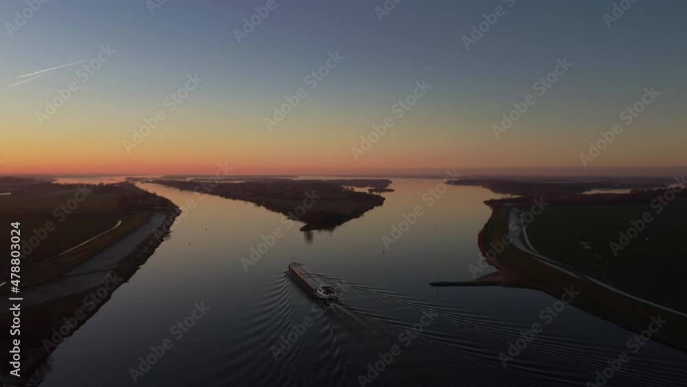Aaerial view on a ship sailing on the river Ijssel during sunrset during a cold winter afternoon in Overijssel, Netherlands. Aaerial view on a ship sailing on the river Ijssel during sunrset during a cold winter afternoon in Overijssel, Netherlands.