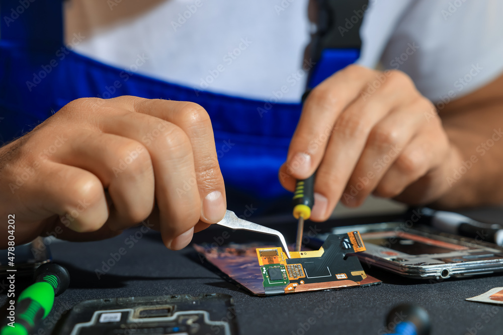 Technician repairing broken smartphone at table, closeup Technician repairing broken smartphone at table, closeup