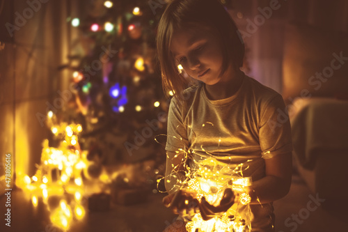 cute girl with garlands in front of the Christmas tree. Indoors, home
