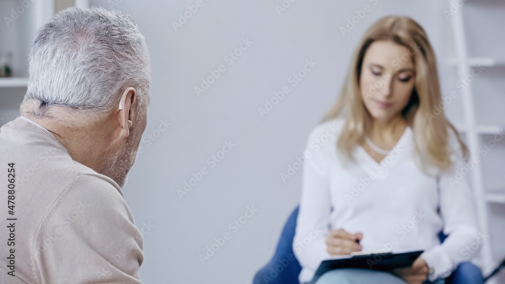 middle aged man near blurred psychotherapist middle aged man near blurred psychotherapist