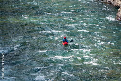 River kayaker in red kayak are paddling whitewatered river, overhead shot. Extreme sports and adrenaline concept.