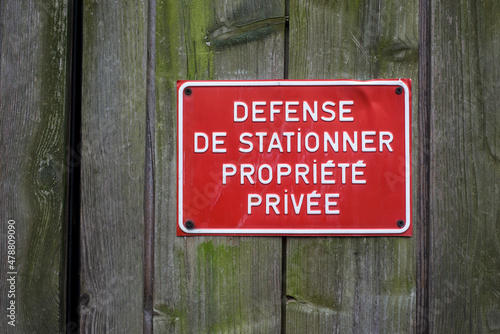 Closeup of private property panel in french (defense de stationner propriete privee) on wooden door traduction in english no parking private property