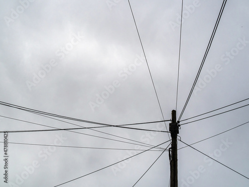 Telegraph pole with many cables, urban street.