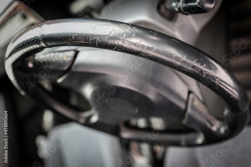 Threadbare automotive black leather steering wheel of old auto close-up