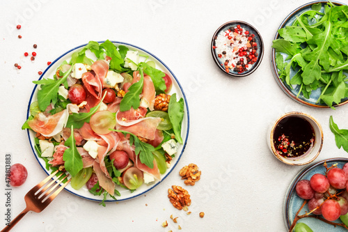 Freash grape salad with jamon, blue cheese, arugula, nuts on white table background, top view, copy space
