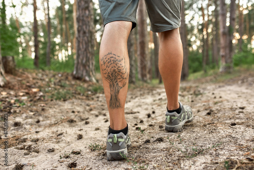 Muscular legs of caucasian man trekking along path