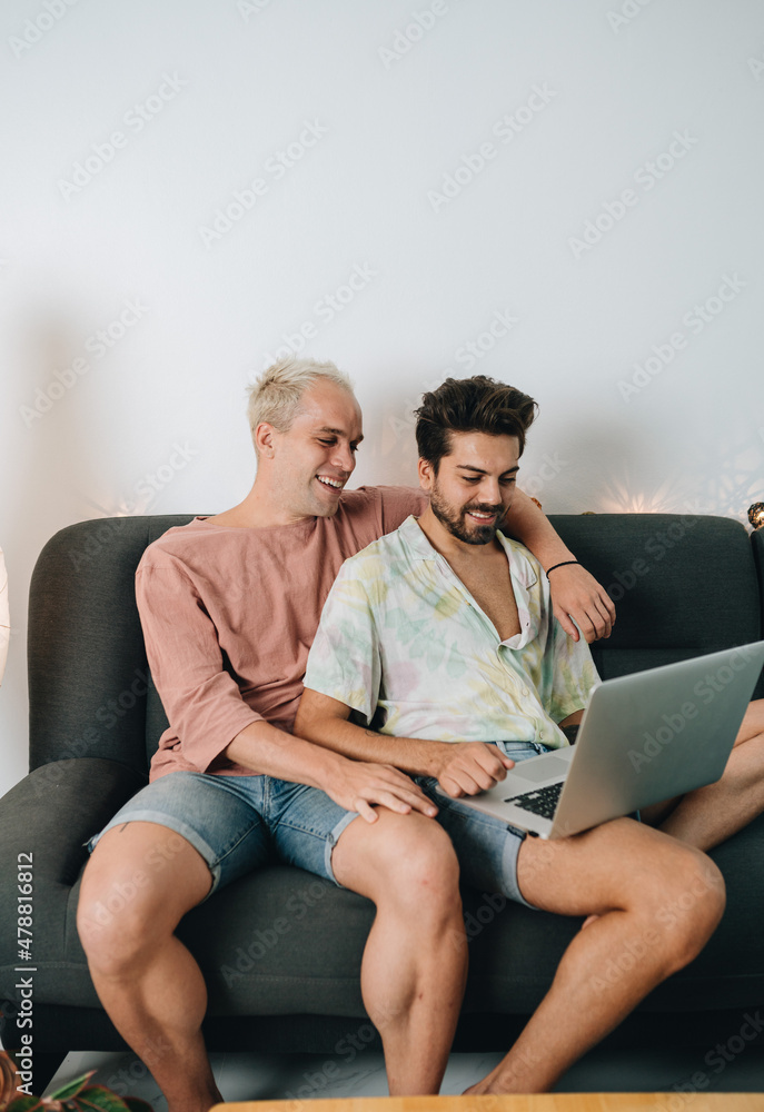 Gay couple sitting on sofa with laptop Gay couple sitting on sofa with laptop