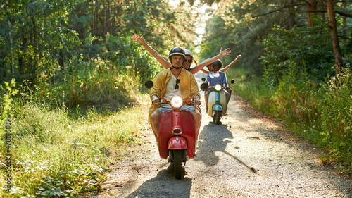 Photography Happy young multiracial couples riding retro scooters