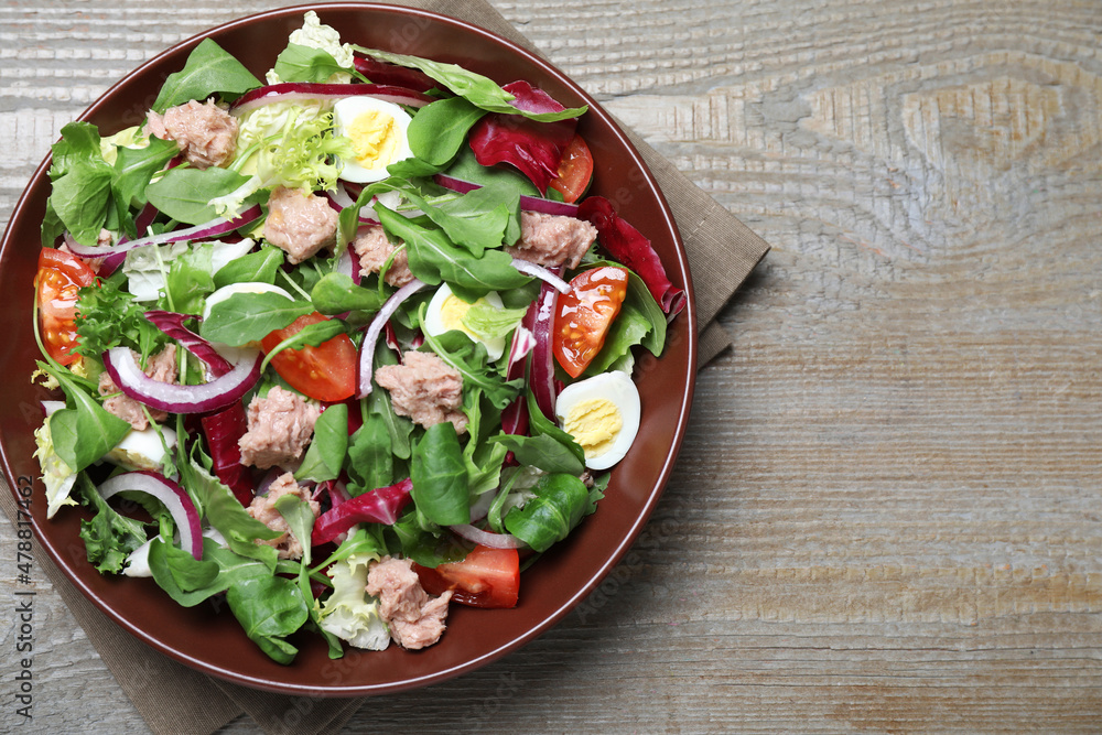 Bowl of delicious salad with canned tuna and vegetables on wooden table, top view. Space for text