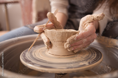 Photo Close up of female hands of an artist making ceramic bowl on potters wheel