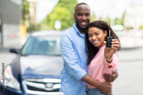 Happy black couple standing near car showing keys