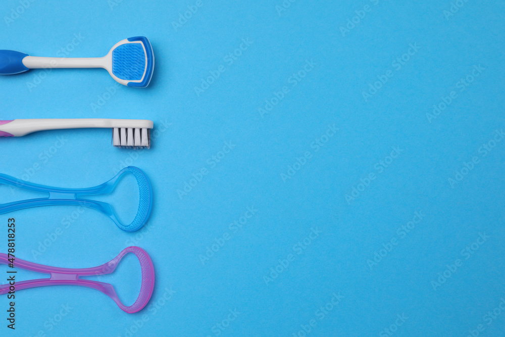 Tongue cleaners and toothbrush on blue background, flat lay. Space for text